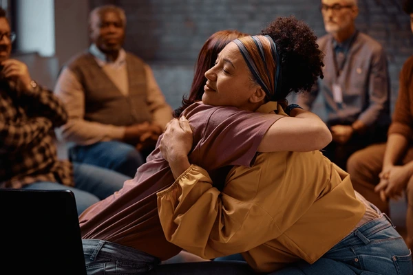 Two women hugging in group therapy